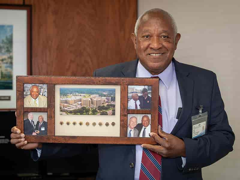Mr. Ivory Bogan holding a photo frame displaying his many years of service pins